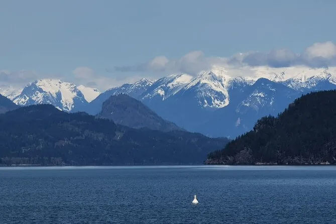 Montagnes enneigées au-dessus de rivages boisés sombres et d'eau libre