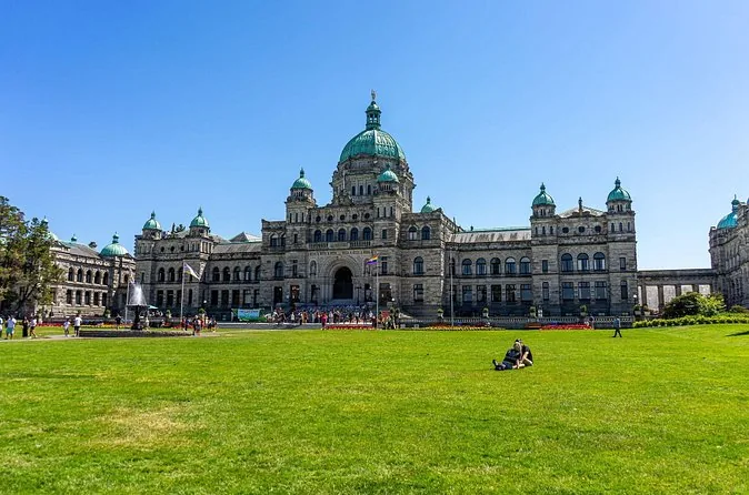 The domed Parliament Buildings behind a wide green lawn on a sunny day