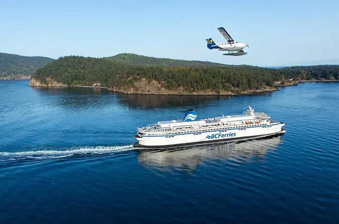 A BC Ferries ship crossing open water near a wooded island while a floatplane flies above