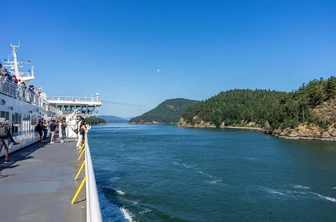 View from a ferry deck towards forested islands on a sunny day